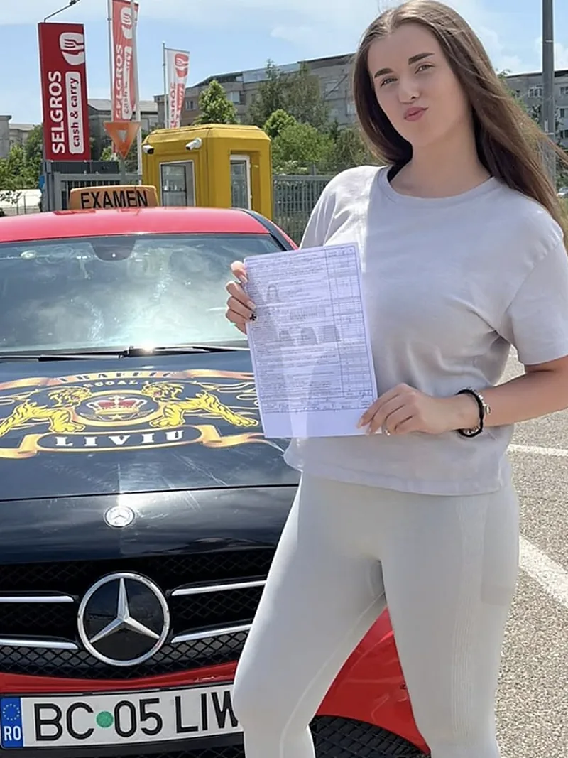 Cursantă cu fișa de examen promovată, lângă mașina școlii Traffic Liviu
