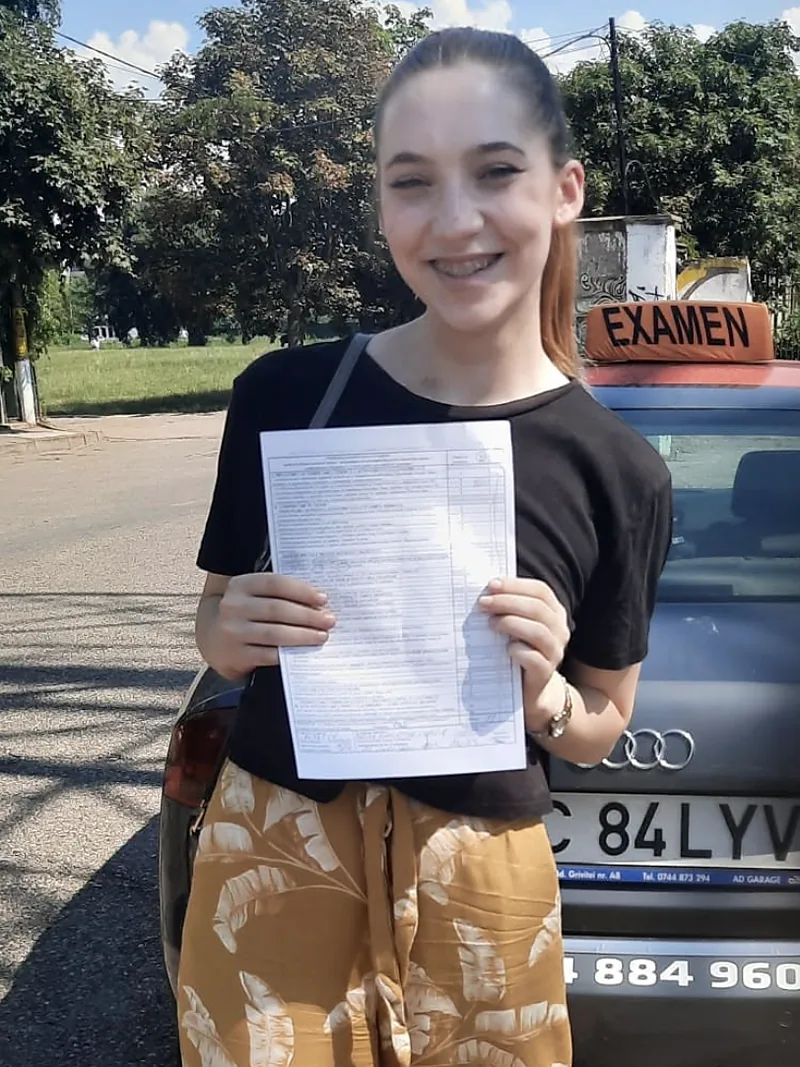 Cursantă care tocmai a promovat examenul, lângă mașina școlii