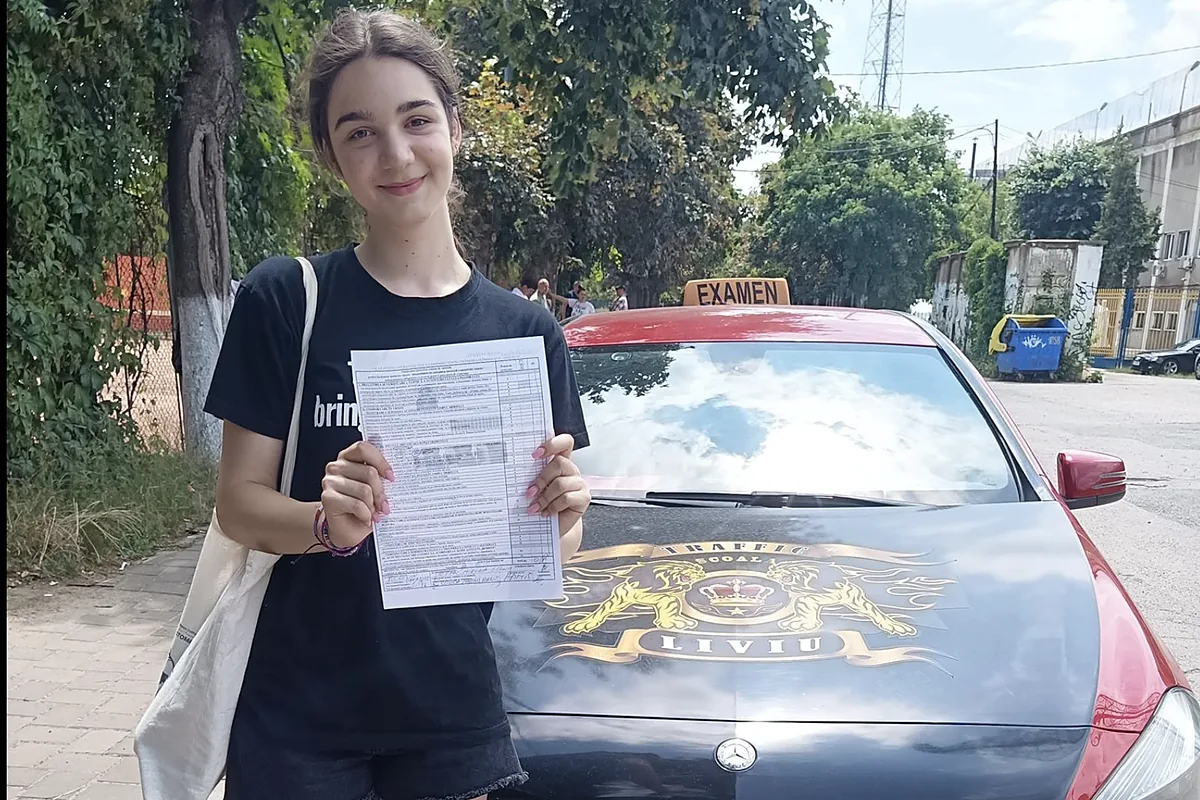 Mercedes Clasa A roșu-negru al școlii, cu stema Traffic Liviu pe capotă și caseta EXAMEN pe plafon